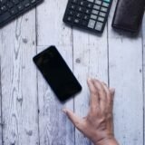 Telefon mobil vechi așezat pe un birou din lemn, pregătit pentru resetare înainte de vânzare
