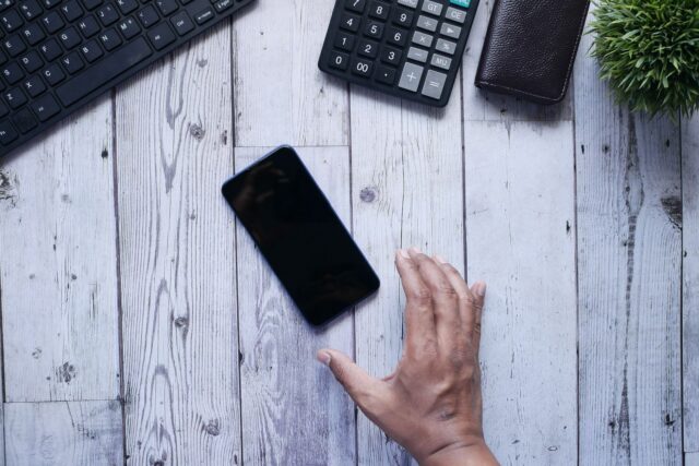 Telefon mobil vechi așezat pe un birou din lemn, pregătit pentru resetare înainte de vânzare