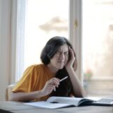 Trusă de prim ajutor deschisă pe o masă, cu plasturi, comprese sterile, fașă și termometru