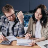 Un cuplu tânăr analizează împreună facturile și bugetul familiei la masa din bucătărie
